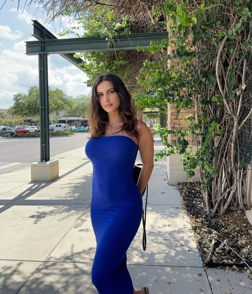 Violet Moore in a fitted blue dress outdoors